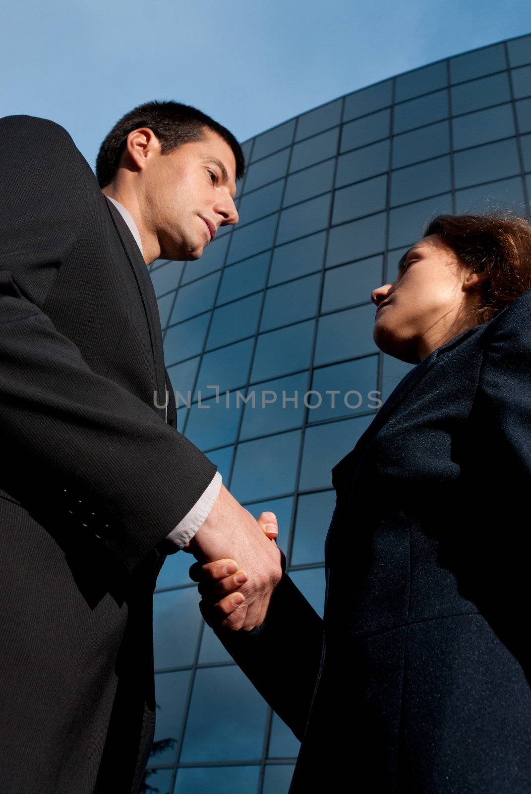Handshake business man and woman on modern building background