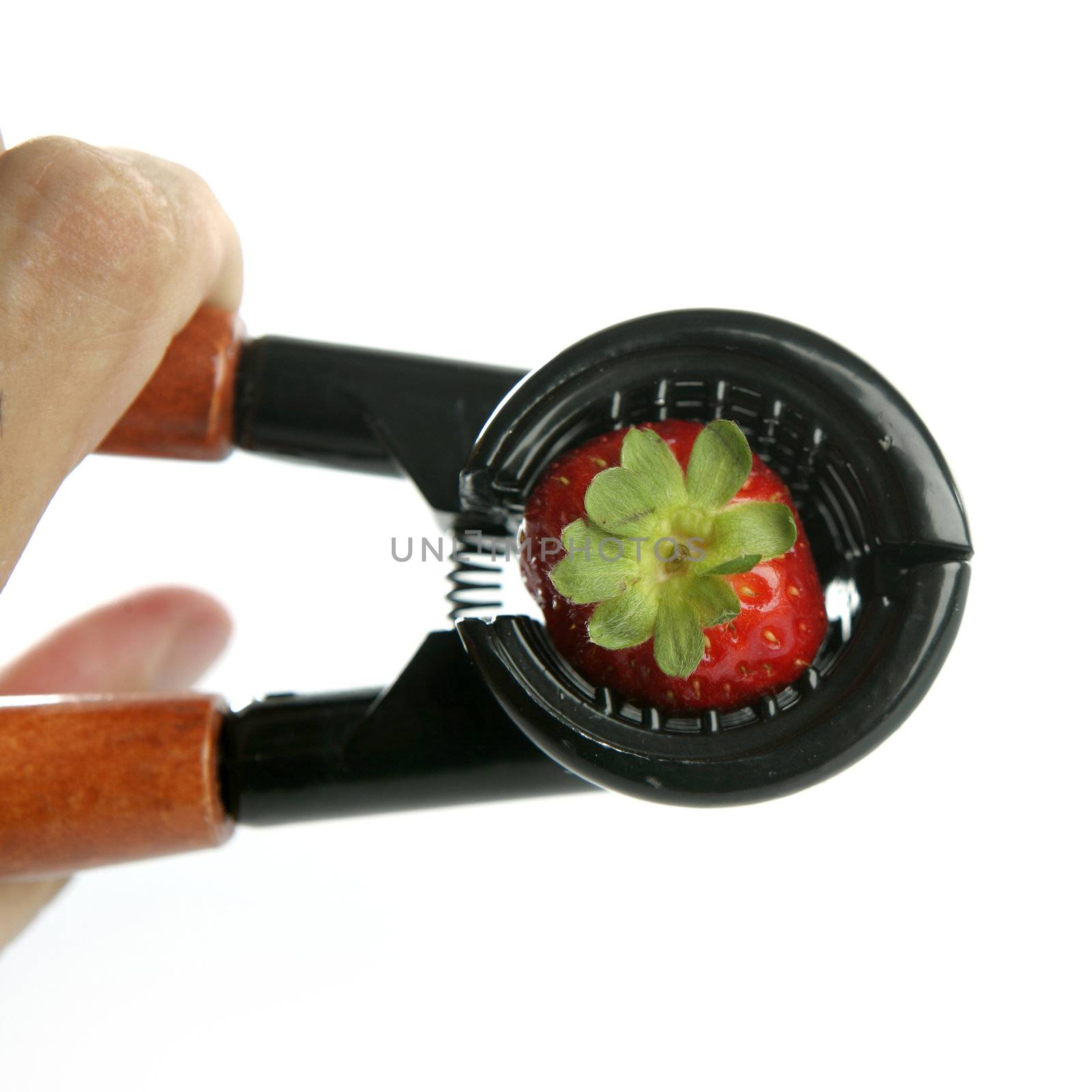 Hand pressuring a strawberry with nutcracker over white background