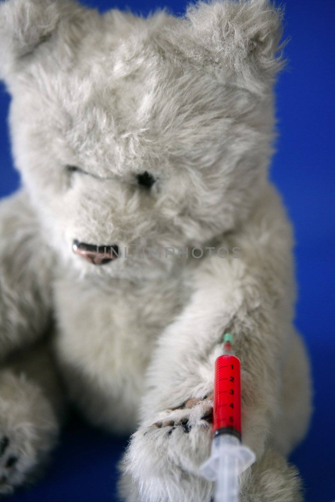 Teddy bear on the doctor, with bloody vaccine syringe on its arm