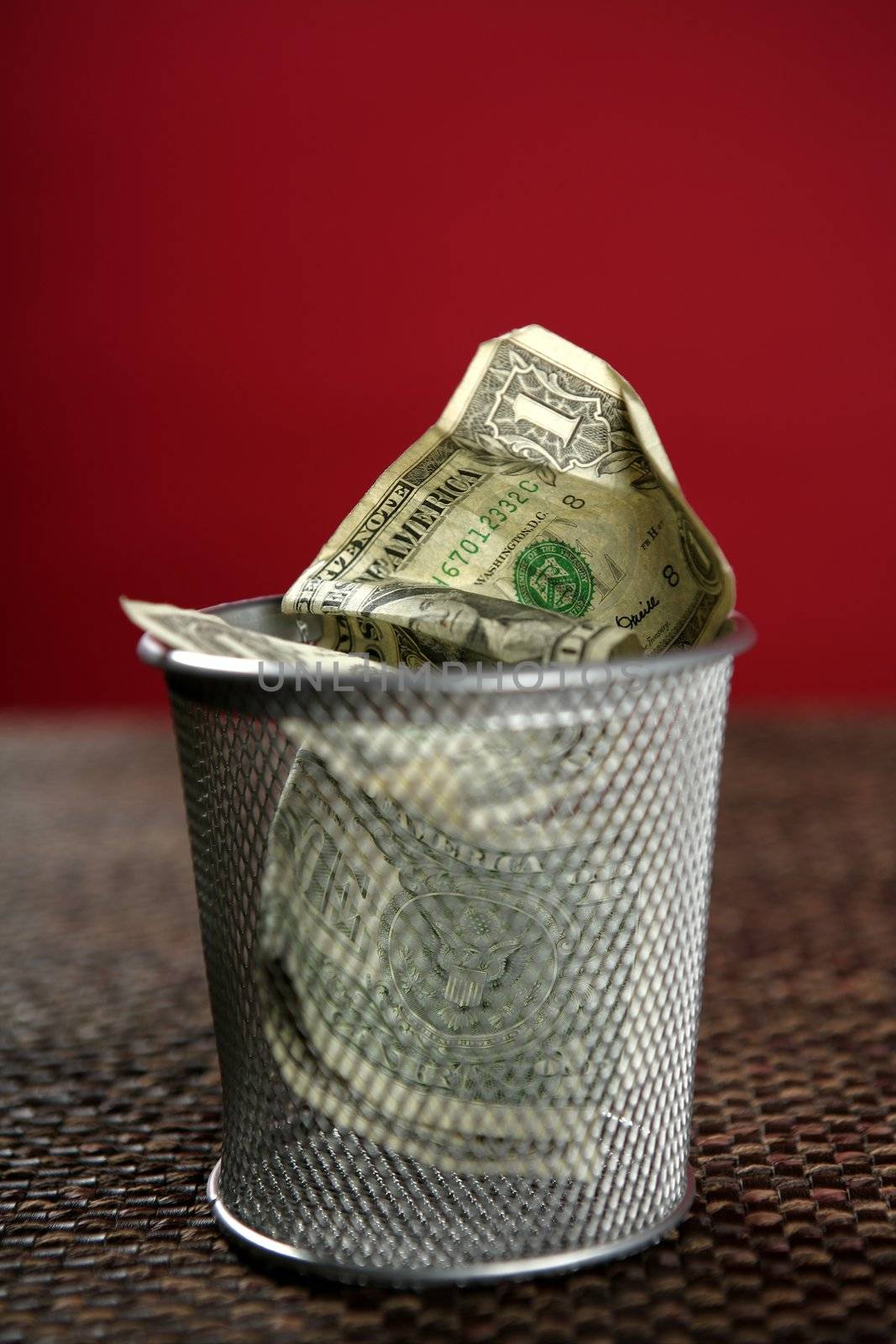 Dollar bank notes on the trash over brown tablecloth, red background