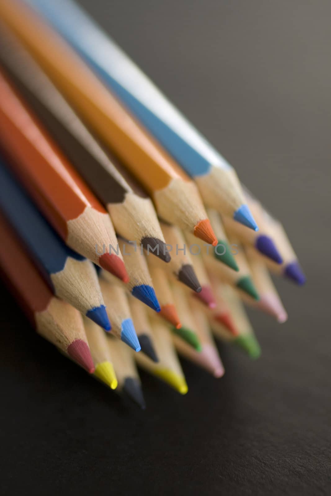 Close up of group of multi-colored coloring pencils isolated on blsck background.