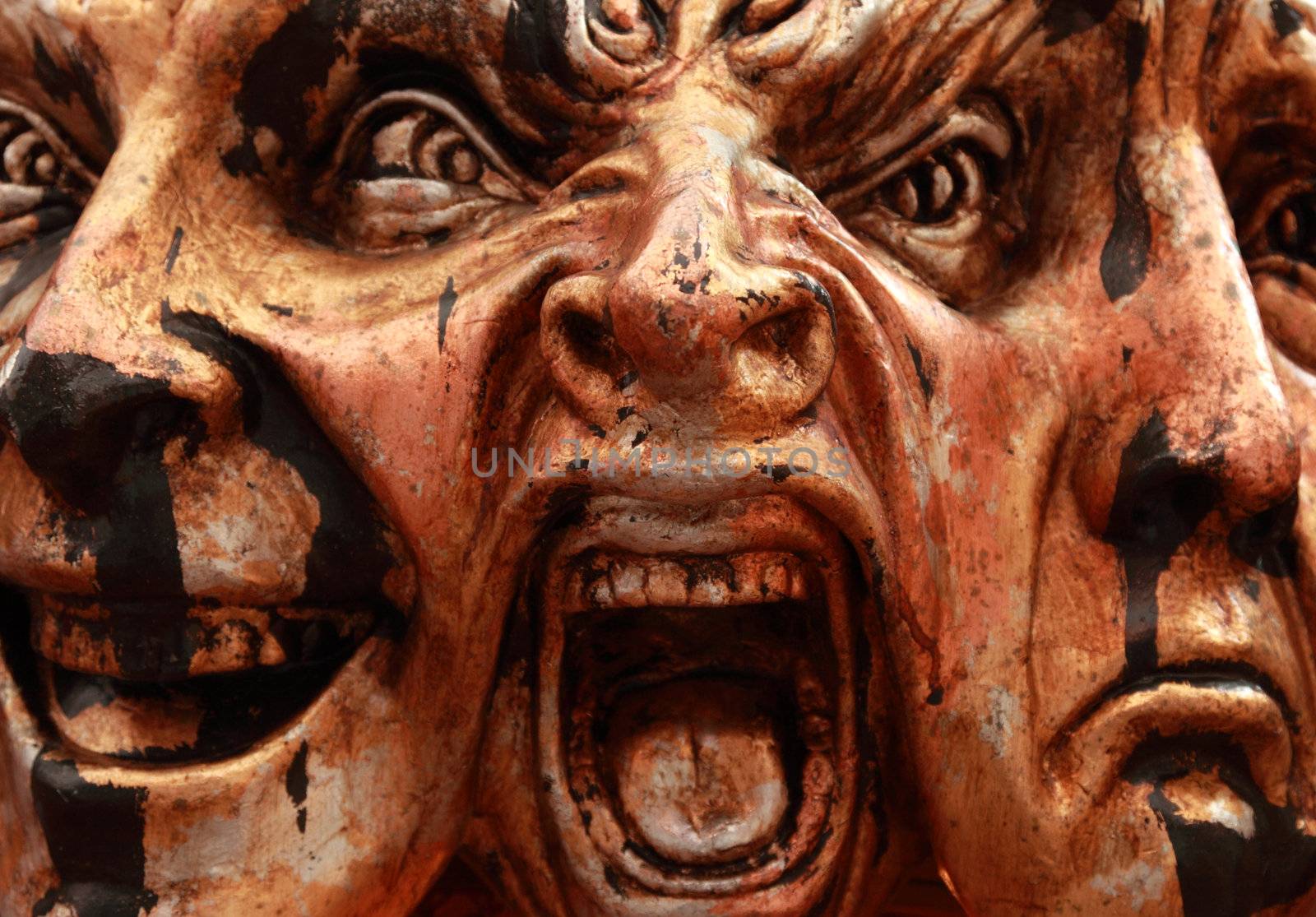 Close-up image of a Venetian mask representing three facial expressions