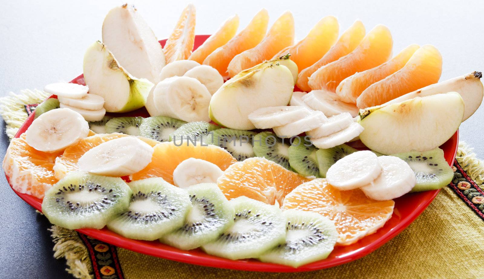 Fresh fruits on plate: apples, pears, bananas, kiwi, oranges