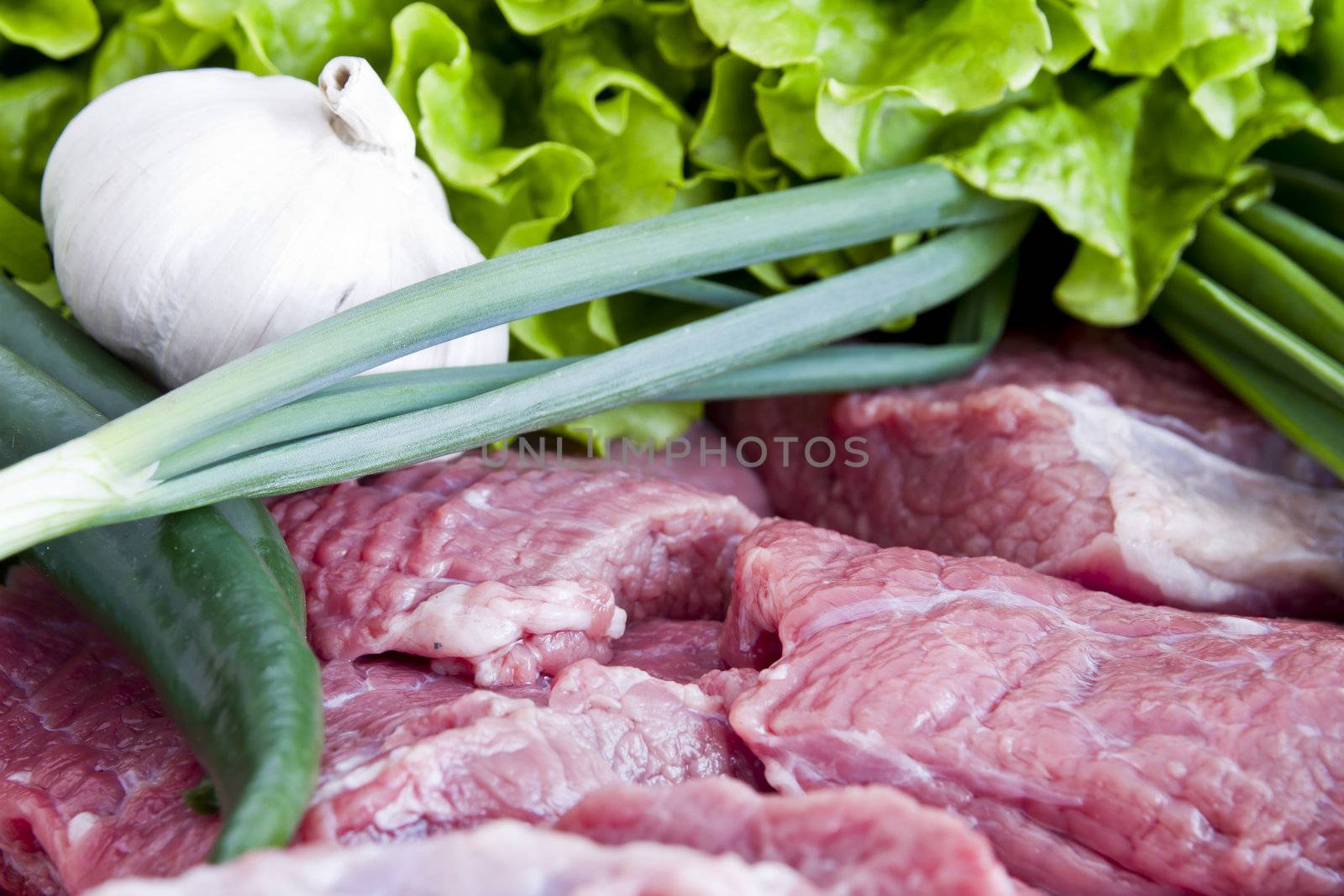 Fresh beef meat with green onion, pepper, garlic and letuce