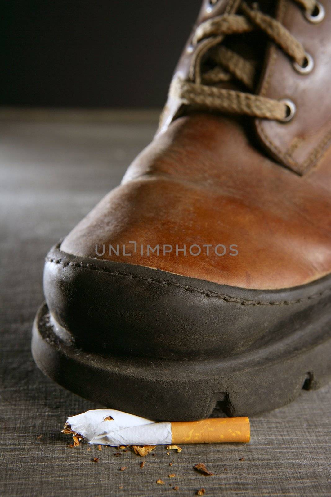 broken cigarette tread by a boot, tobacco addiction metaphor