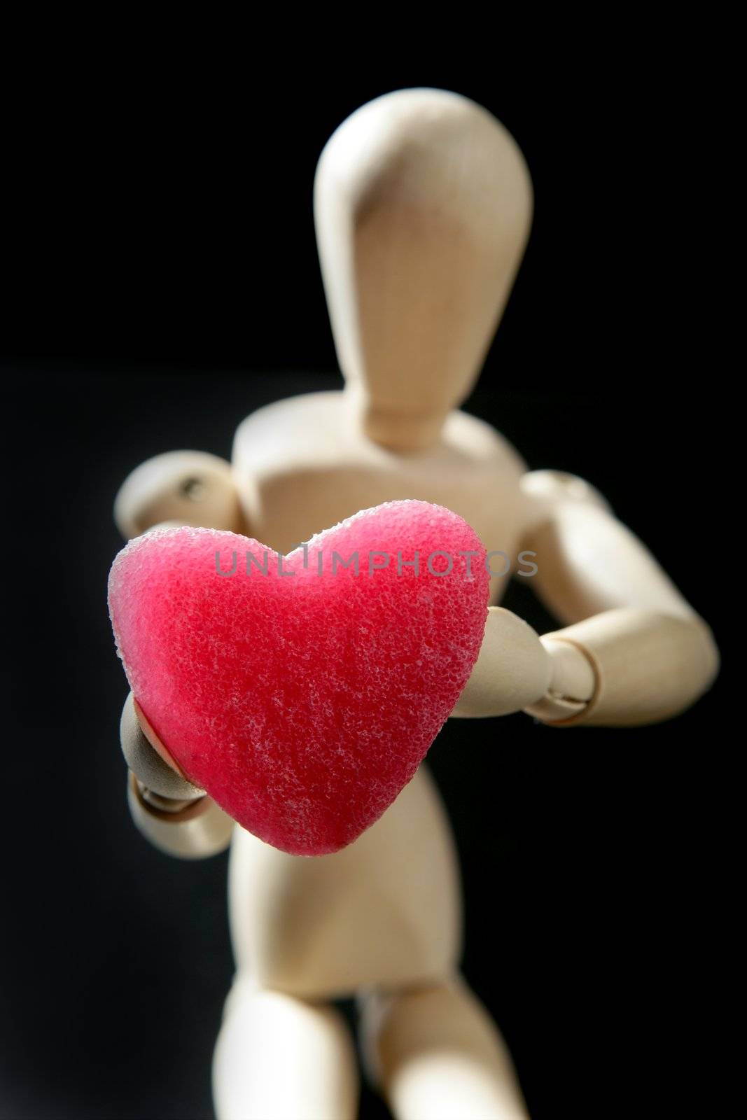 Wooden mannequin holding a red jelly candy heart shaped