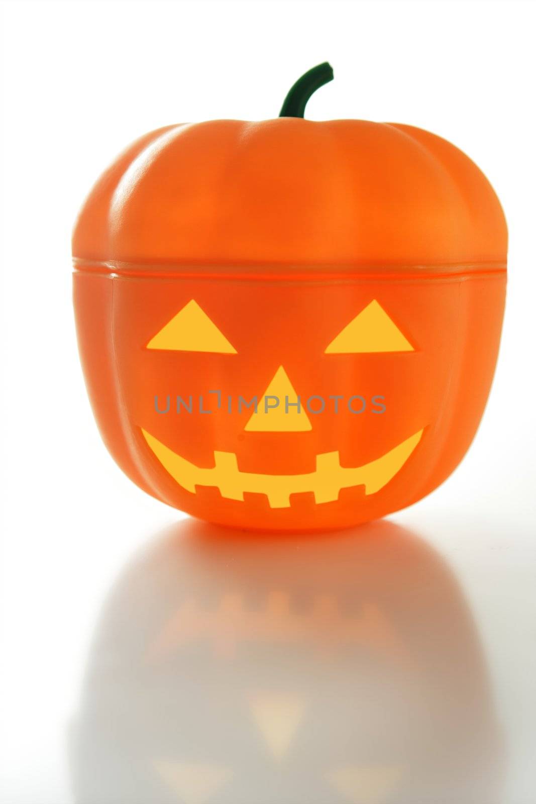 Plastic halloween pumpkin, white background with reflex over table