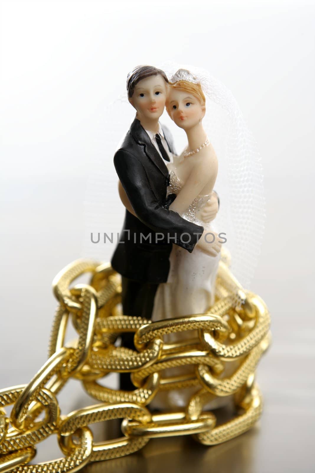 Metaphor of marriage as a loss of freedom. Wedding figurines and golden chain