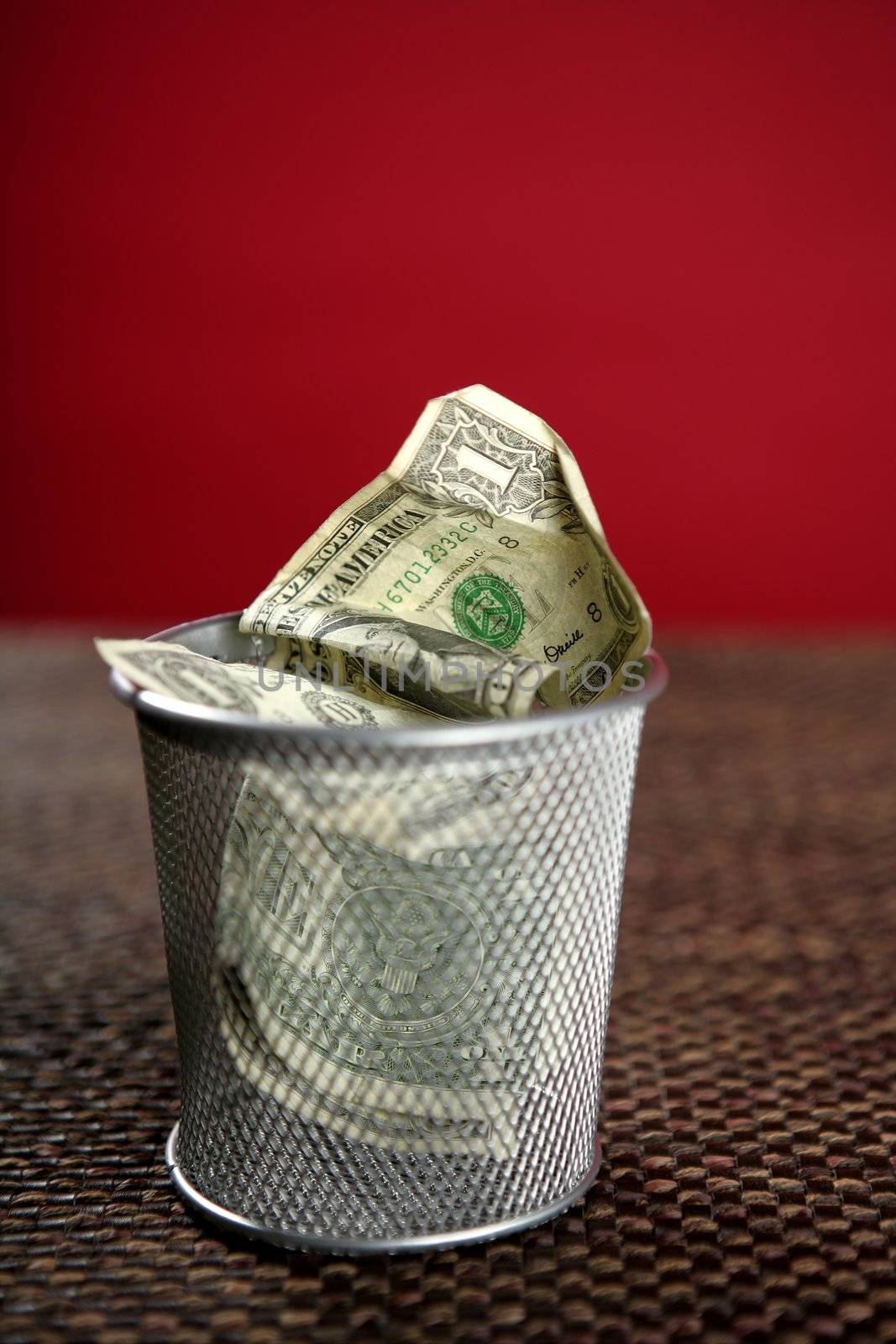 Dollar bank notes on the trash over brown tablecloth, red background