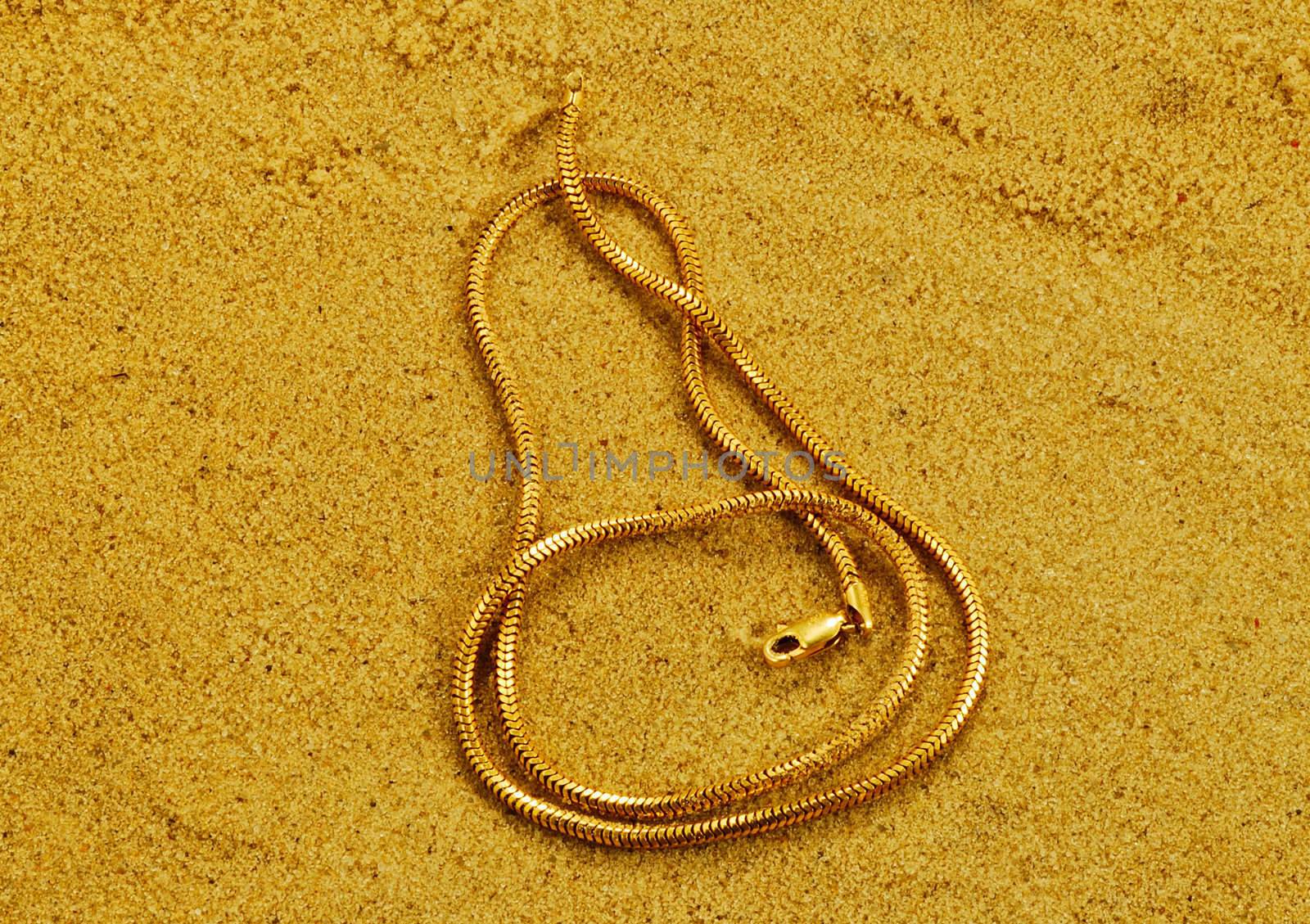 gold chainlets are on yellow loose sand