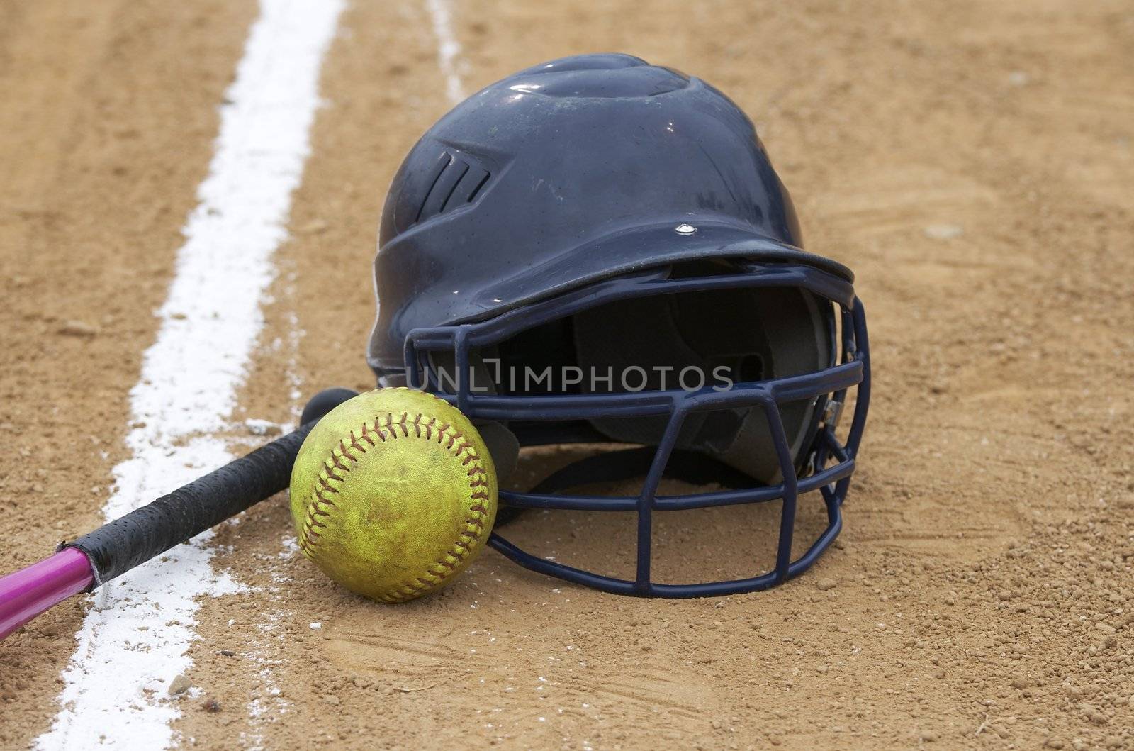 a bat, softball, and helmet on a sports infield