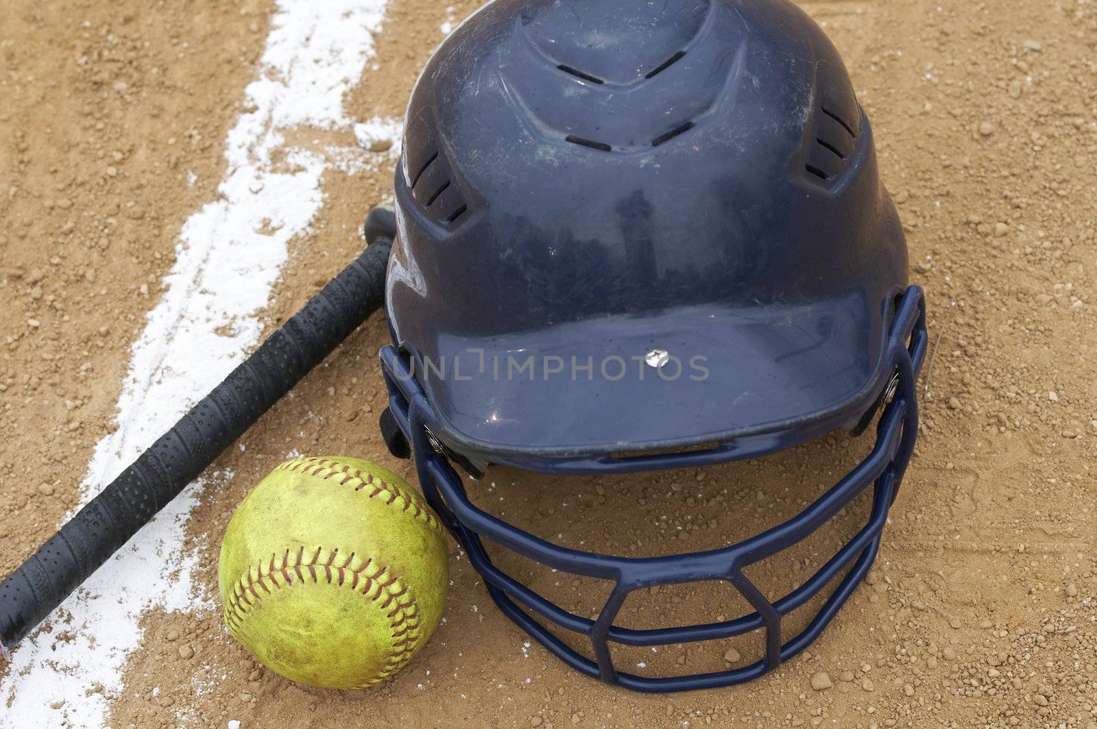 a bat, softball and helmet on the infield