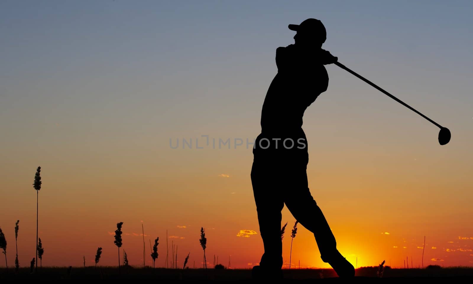 a silhouette of a golfer on a bright sky