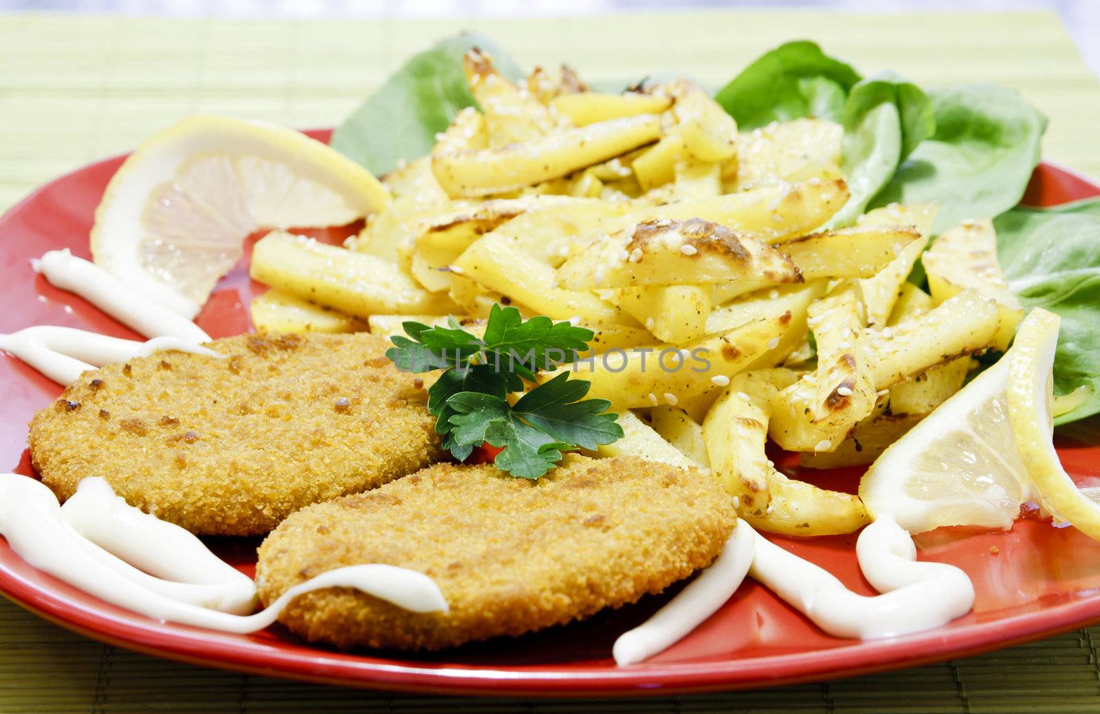 Fish hamburgers with fries, lettuce, lemons, and mayonnaise