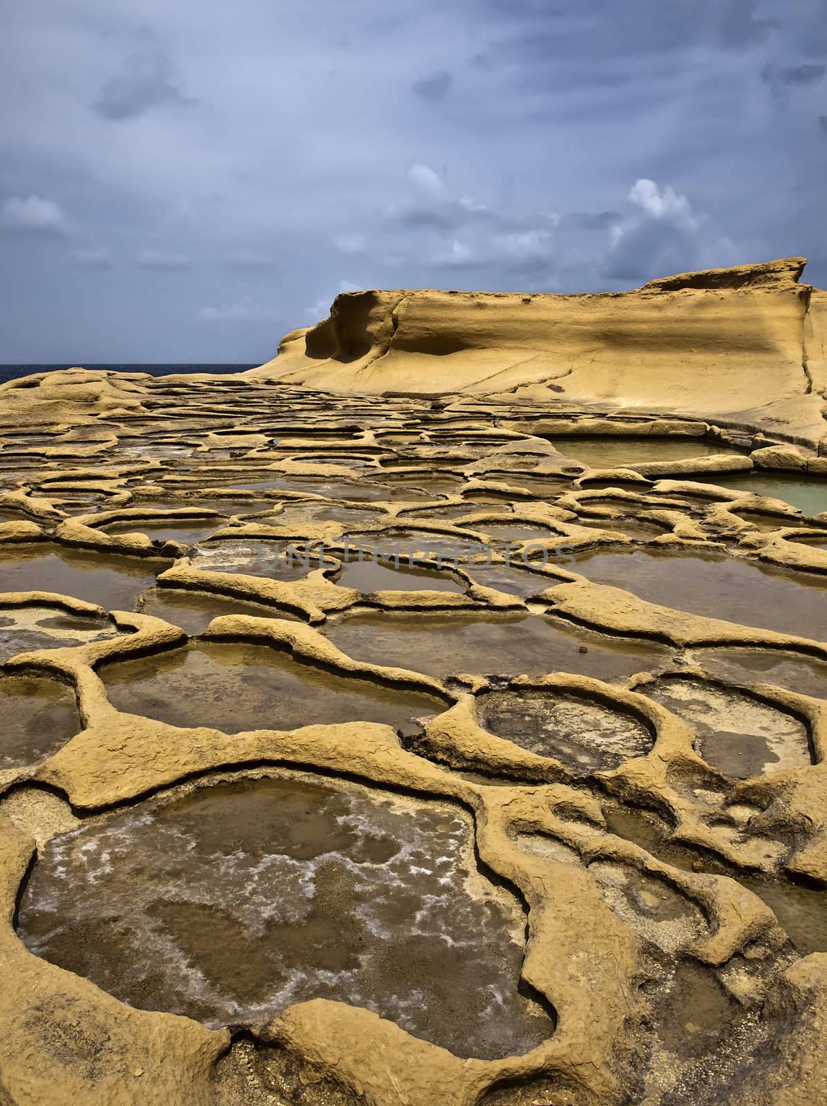 Ancient saltpanes from Roman times carved in sandstone in Qbajjar in Gozo