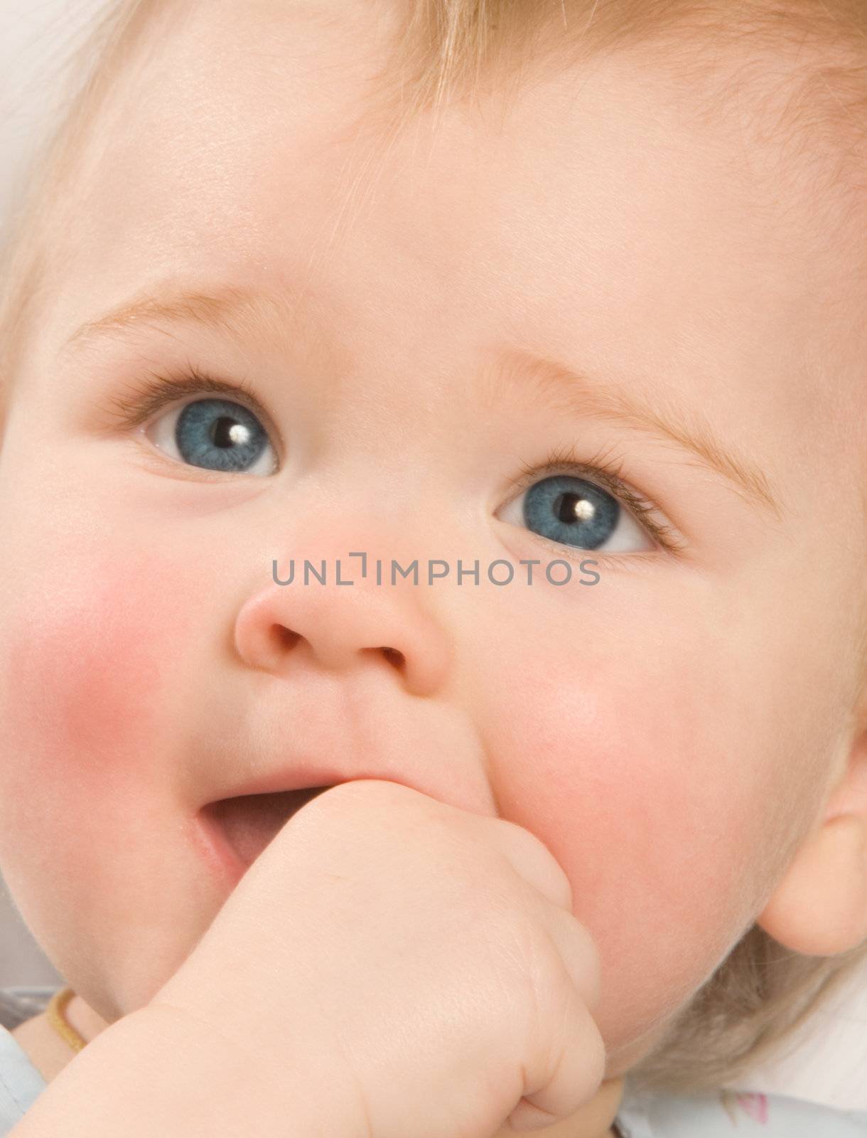 Portrait of the one-year-old girl close up, sucking the hand
