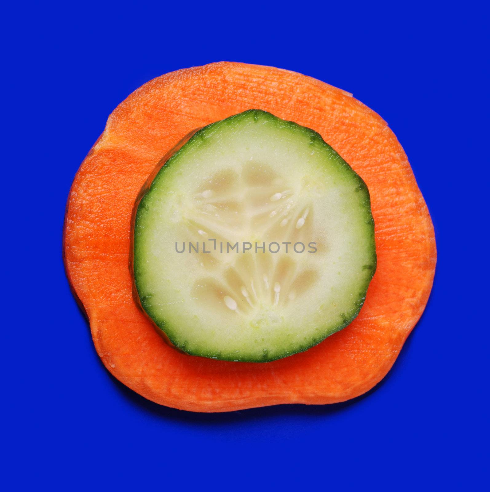 Carrots and cucumber on a dark blue background. Bright paints of a fresh product