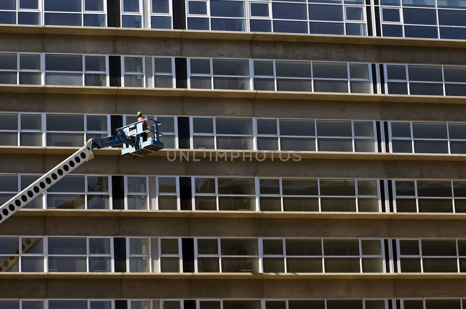Maintenance worker in a crane inspecting a new residential building