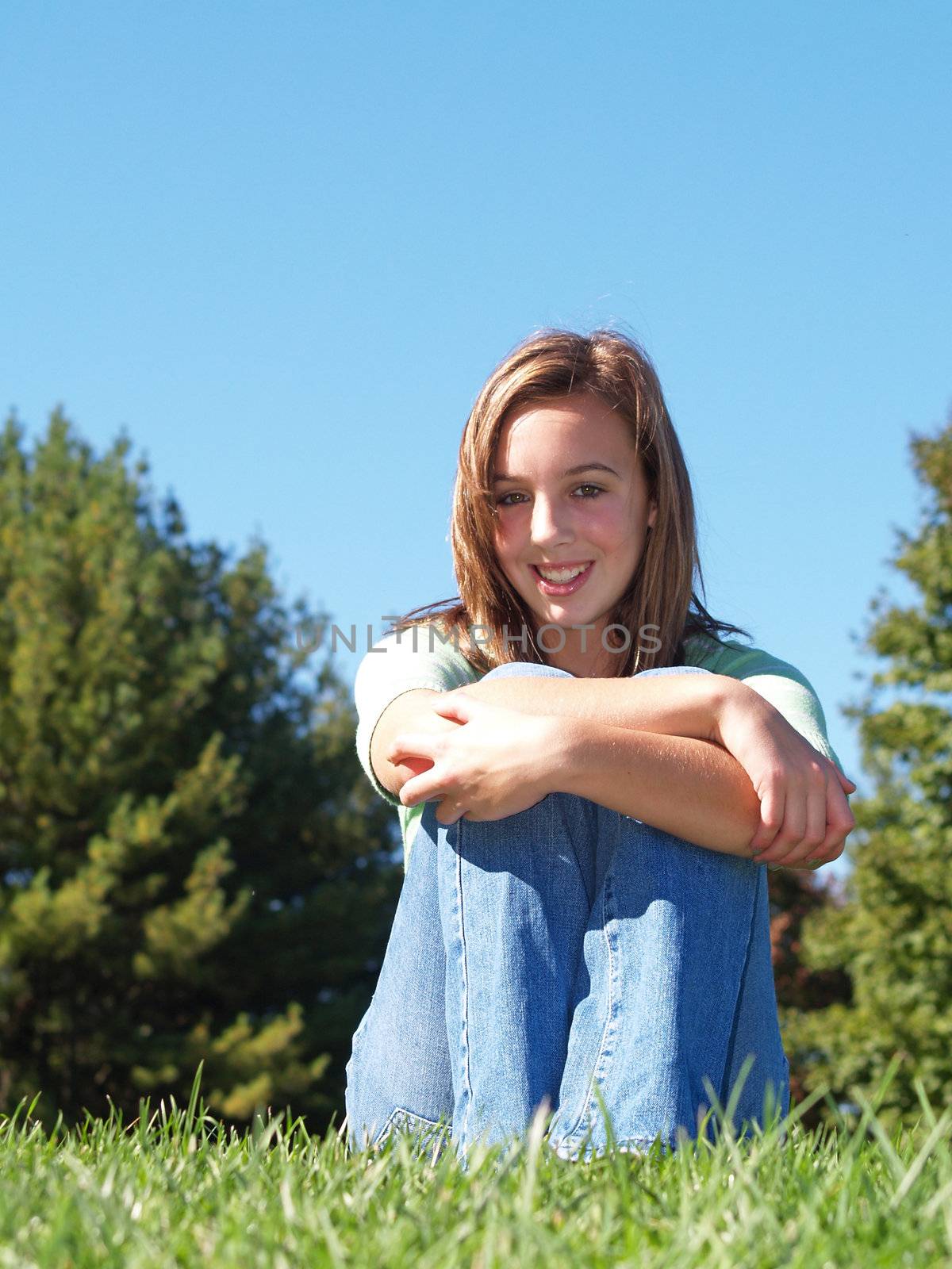 teenage girl sitting in the grass on a sunny day