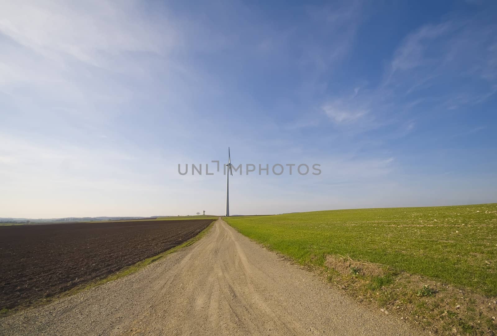 a country lane with a wind turbine in the background