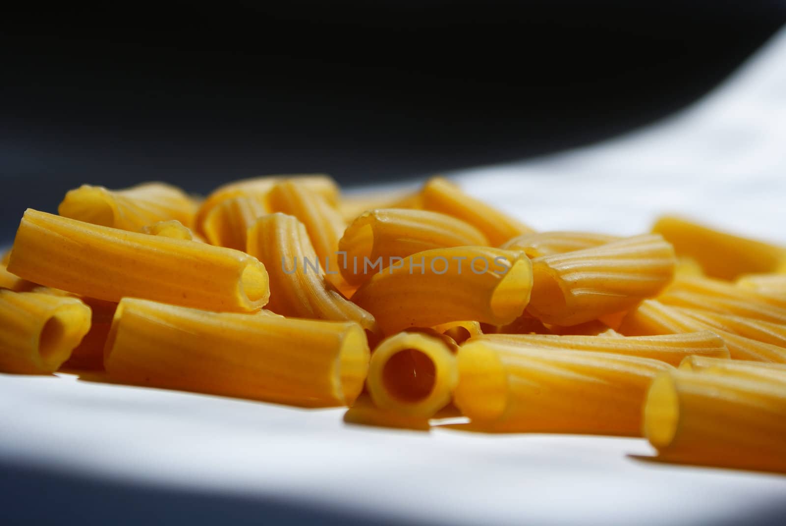 raw macaroni scattered on black and white background
