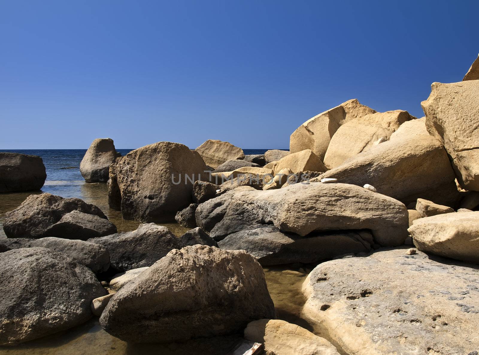 Fallen limestone boulders and rocks near coastline in Gozo in Malta