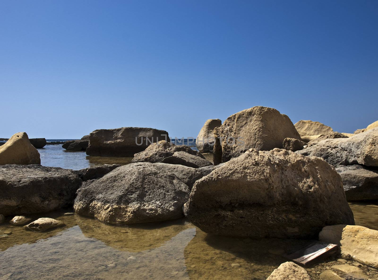 Fallen limestone boulders and rocks near coastline in Gozo in Malta