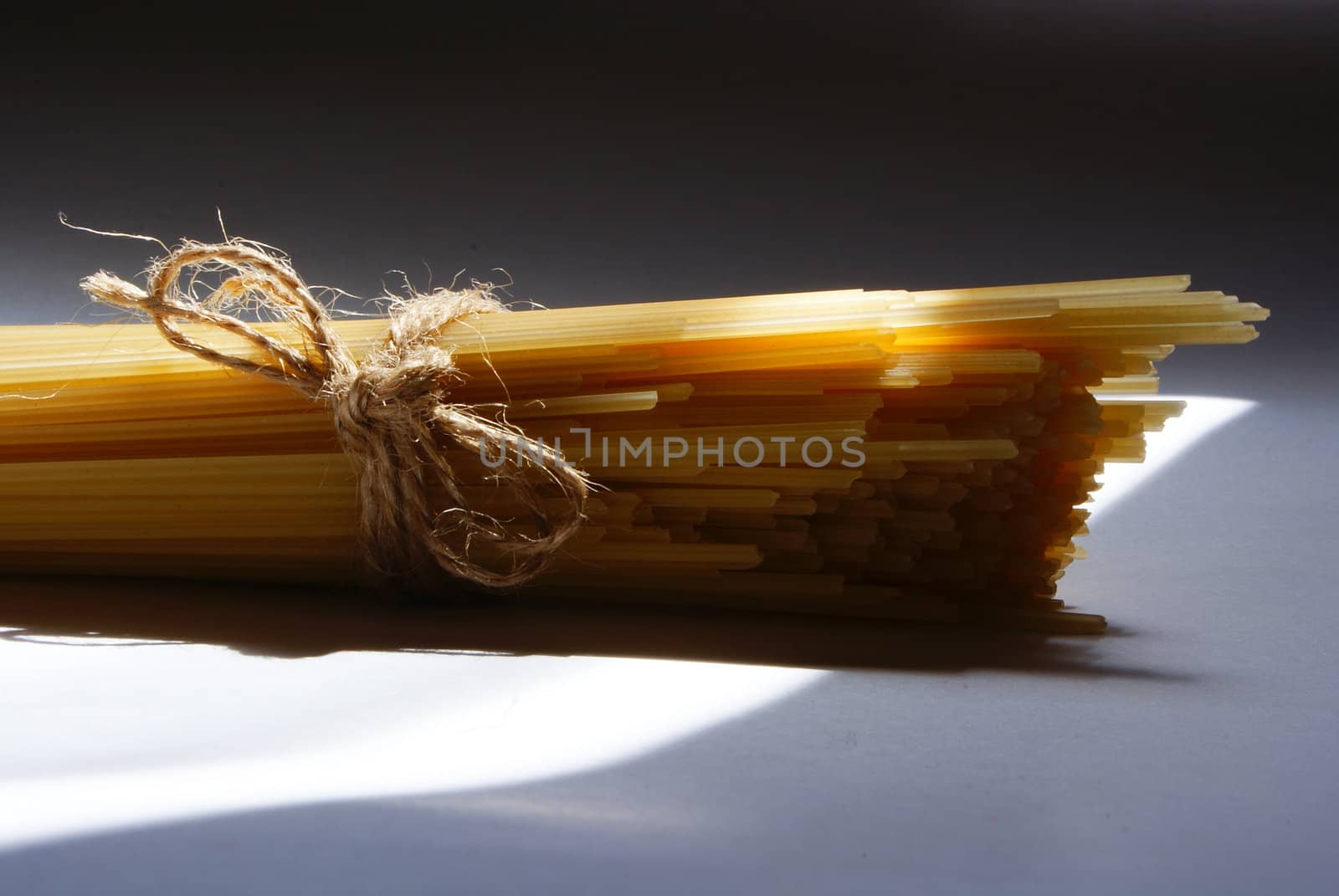 spaghetti pasta sunlit and tied against light and shadow background