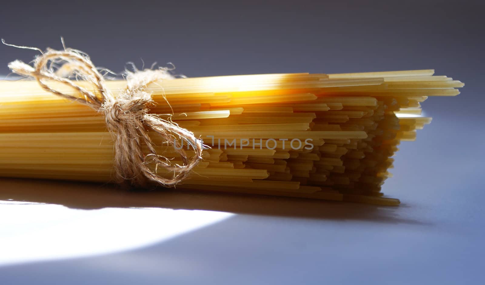 spaghetti pasta tied and sunlit against light and shadow background