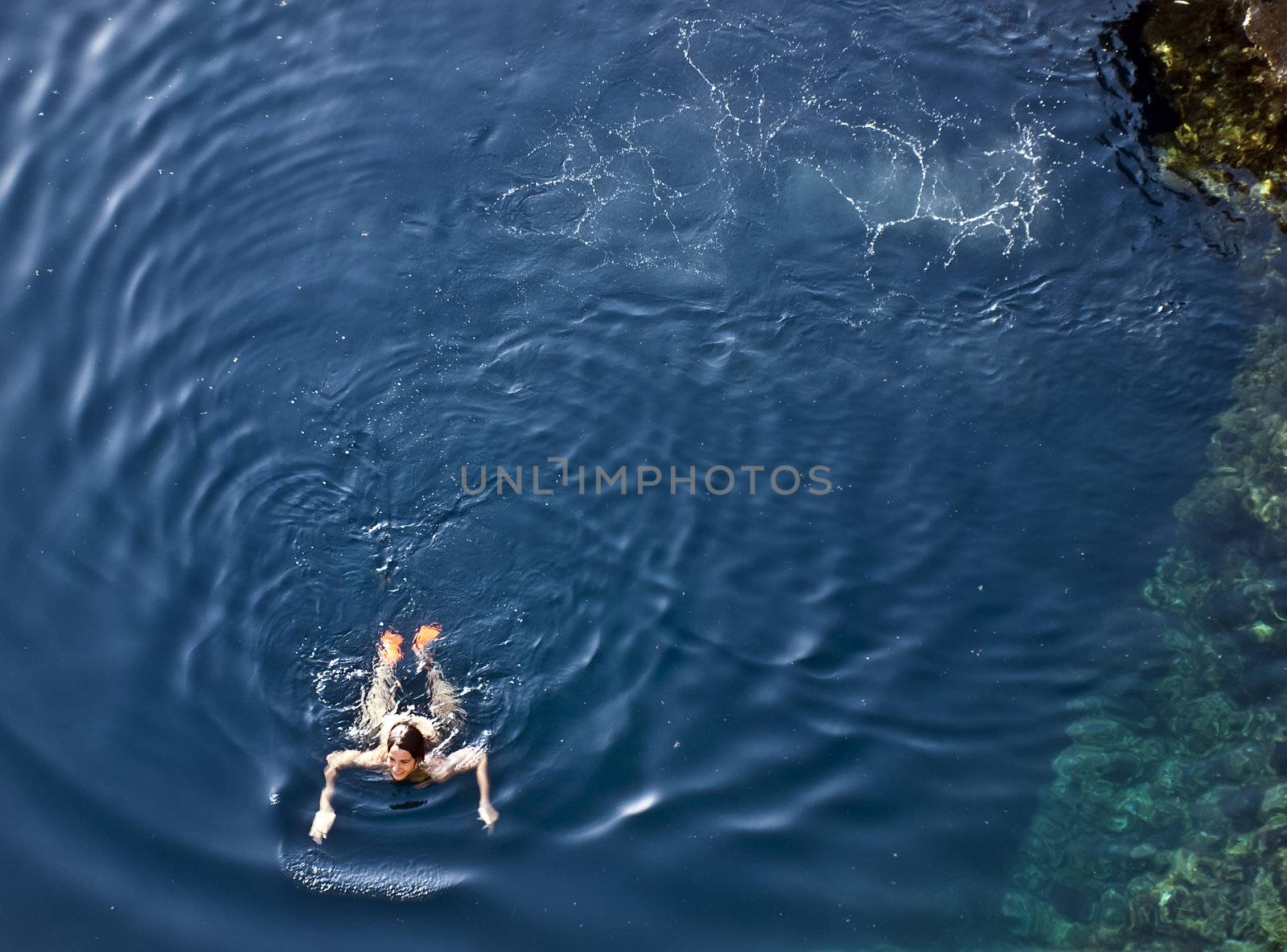 A young woman swimming in crystal clear blue waters