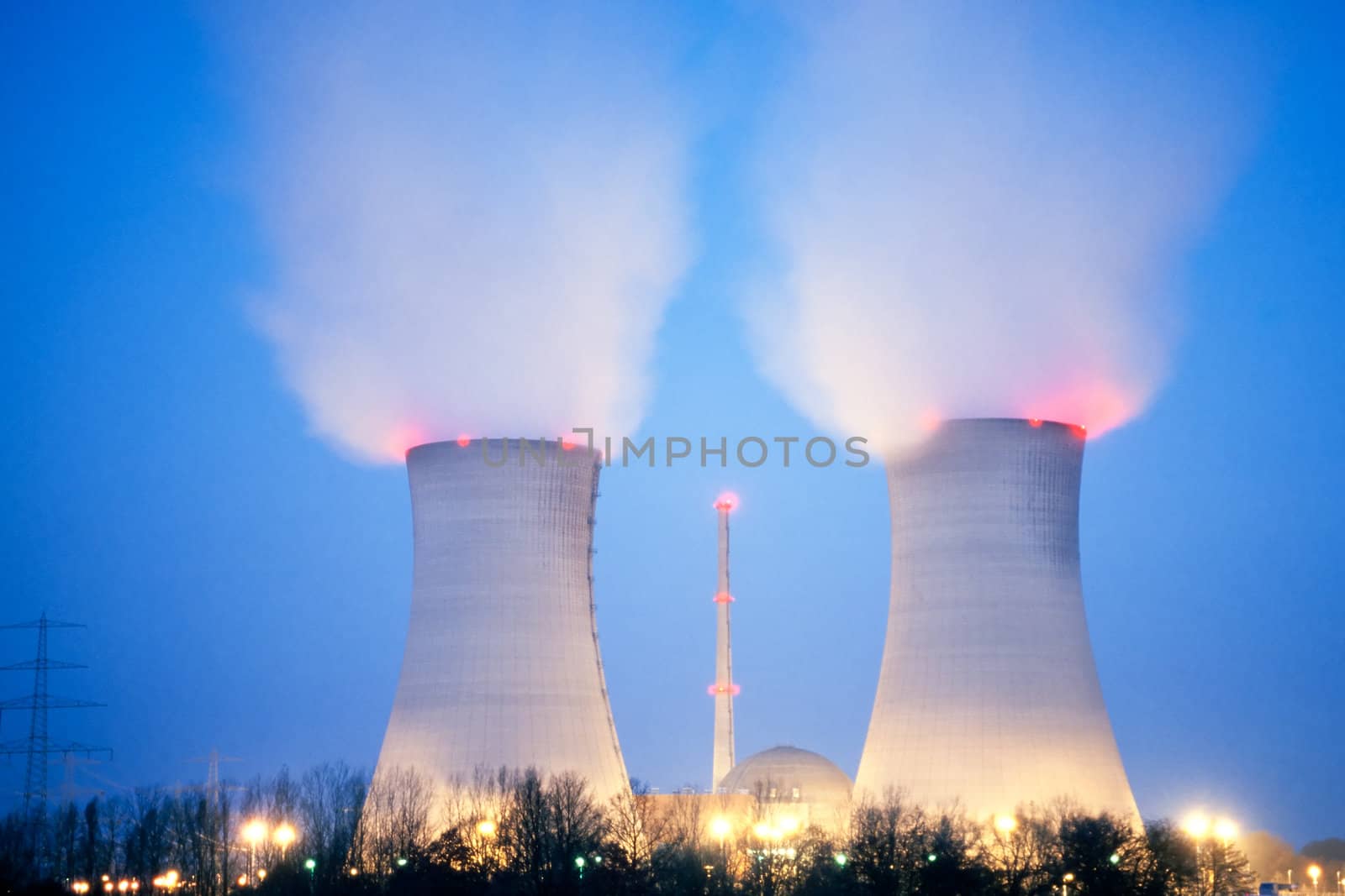 Nuclear power plant blowing huge clouds into dusky sky.