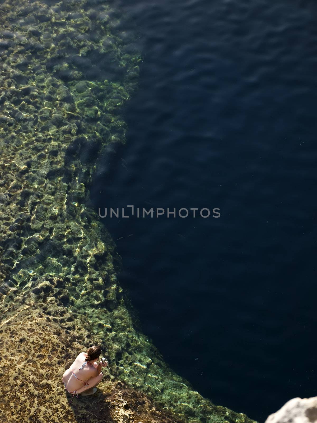 Young Woman looking over the reef in the Blue Hole in Gozo in Malta