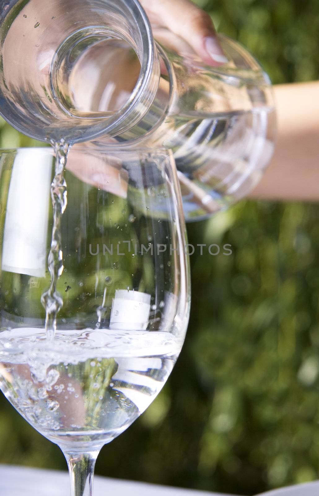 Pouring water into a glass into a wine glass from a carafe