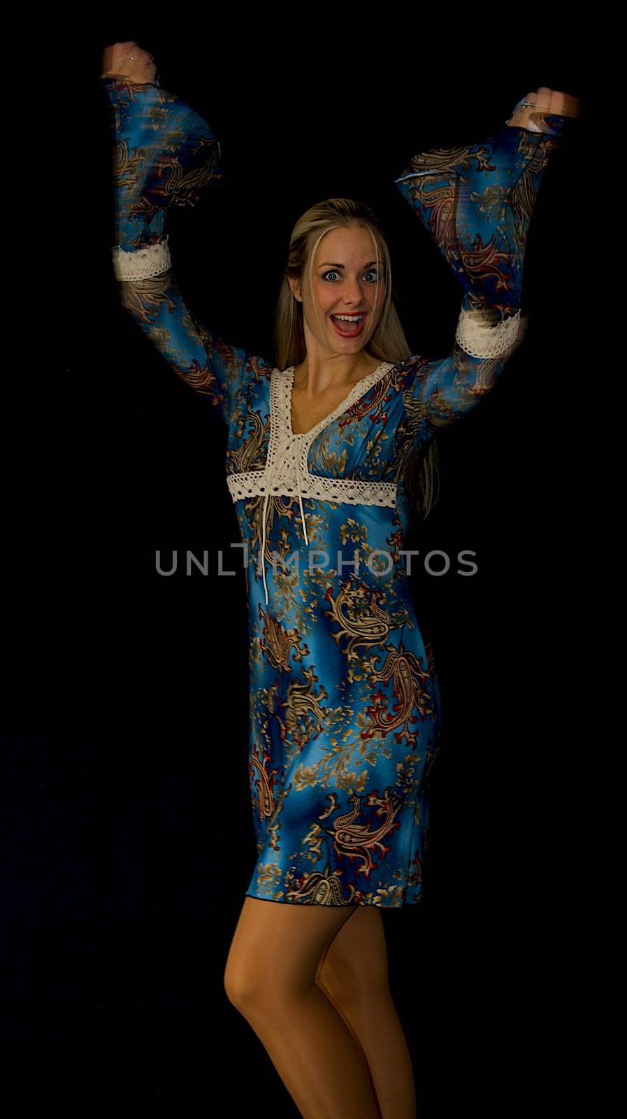 Beautiful blonde woman standing up with arms thrown up in the air in a pose of excitement.