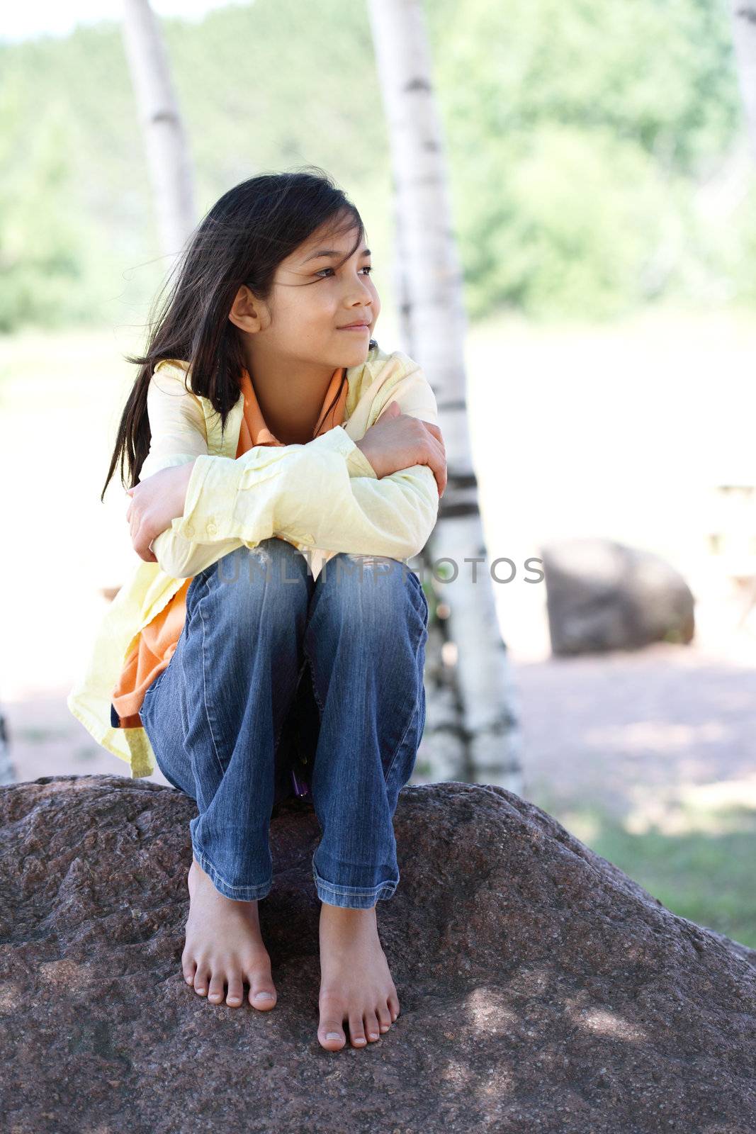 Child sitting under birch trees thinking