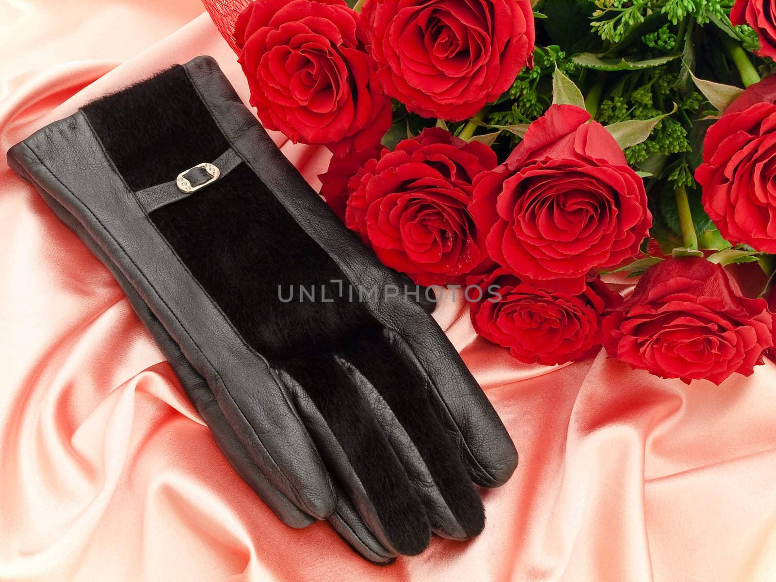 gloves near the red beautiful roses on a pink silk fabric 