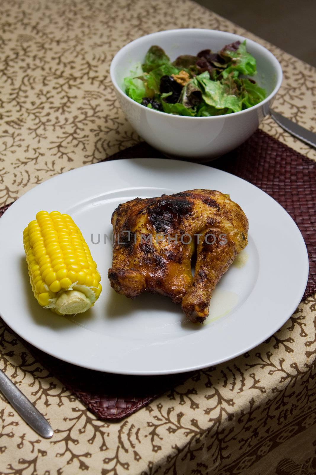 Plate of roast chicken with corn, salad and red wine