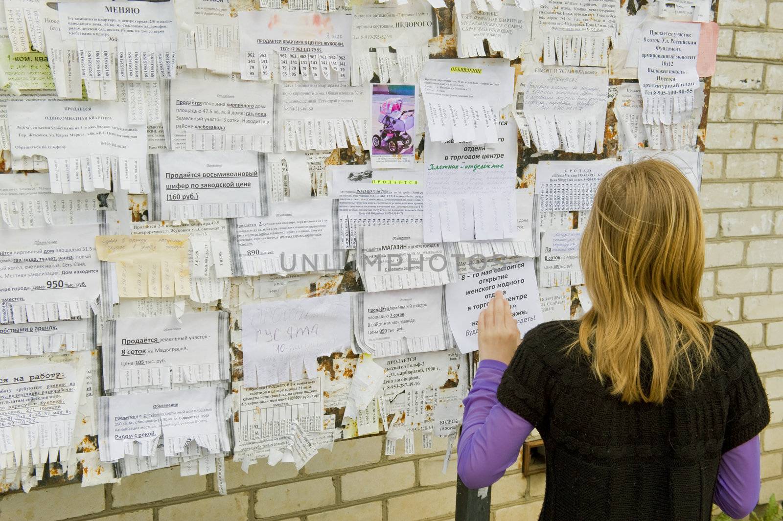 The girl looks through announcements on a board, taketin the Russian province on May 2011