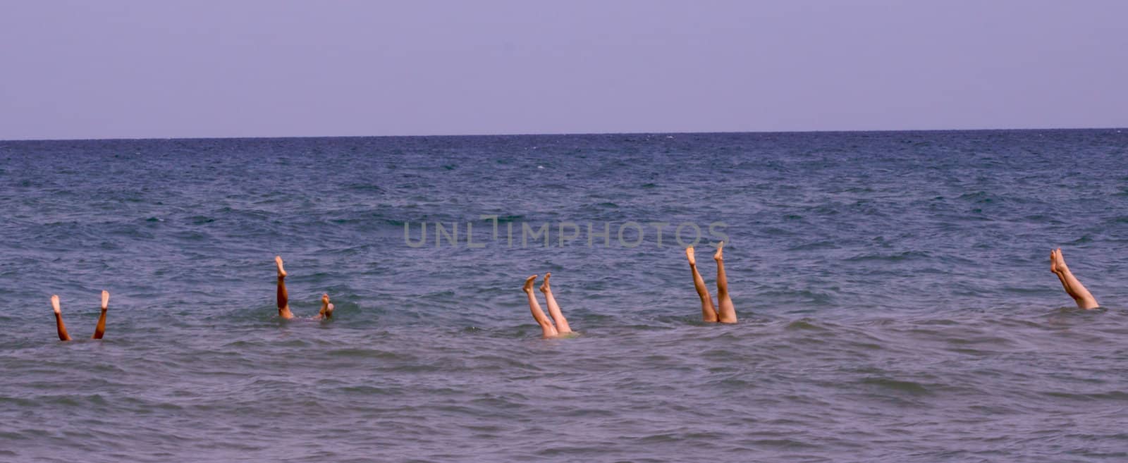 five girls doing attempted handstand on a sandbar in lake michigan