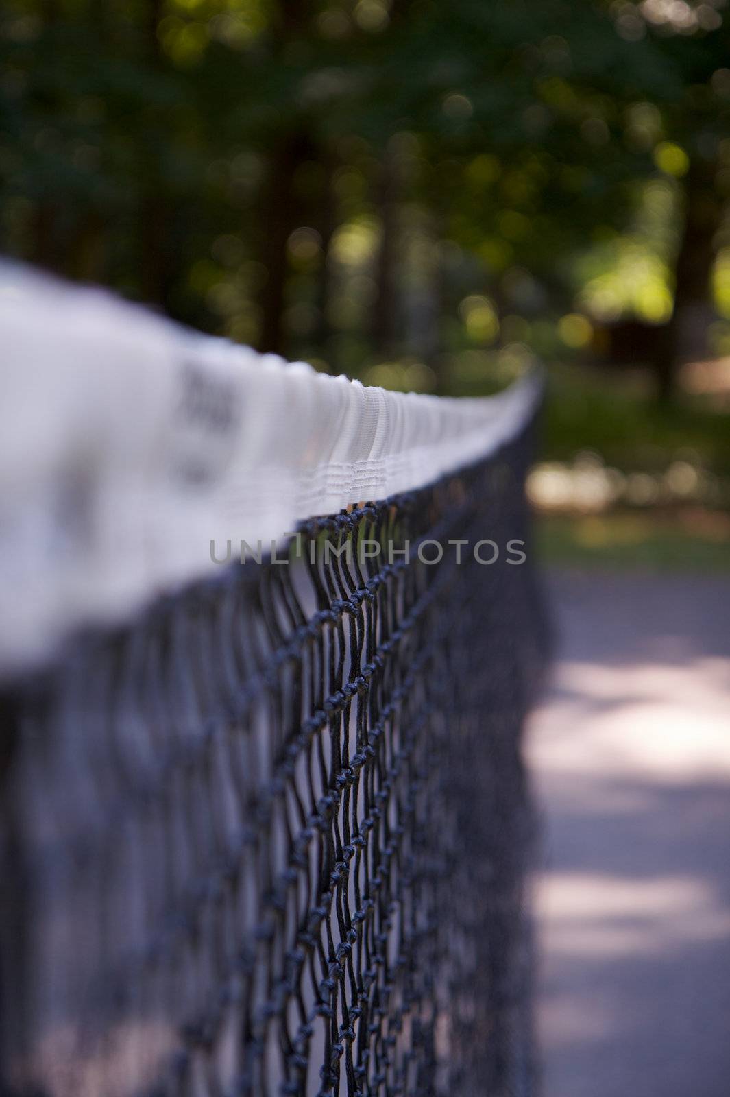 Top of tennis net taken with narrow depth of field with trees in background