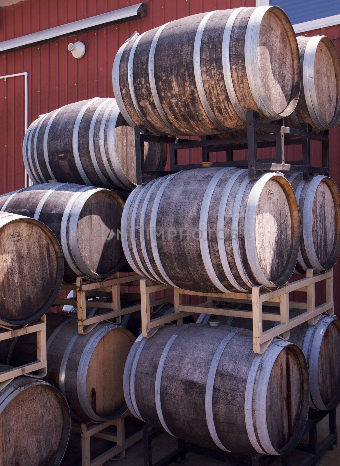 Stacks of wooden wine barrels against winery warehouse