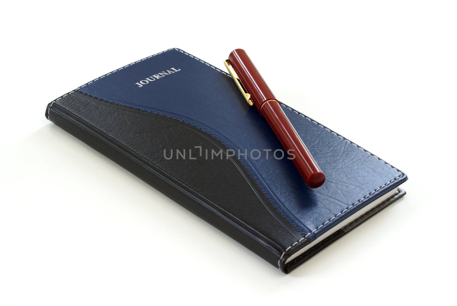 A pen sits on a leather journal.
