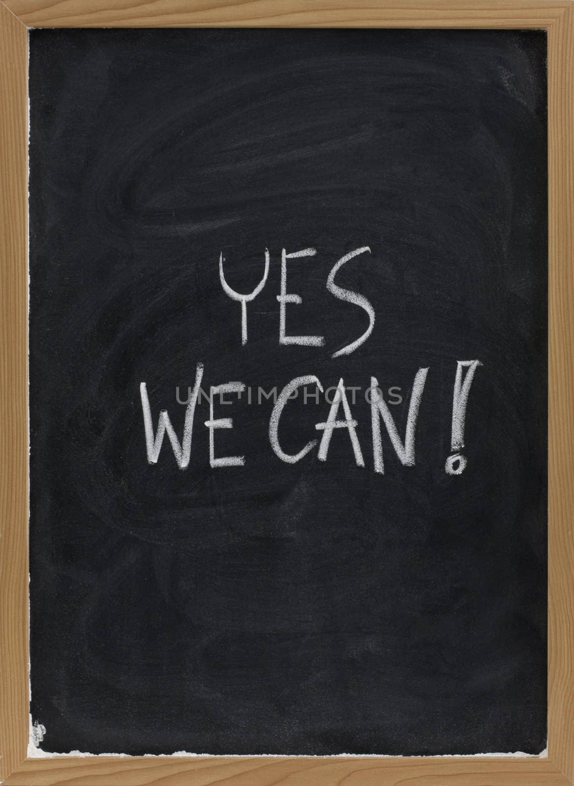 Yes we can - motivational slogan handwritten with white chalk on blackboard with eraser smudges