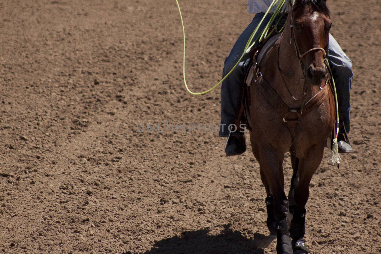 A cowbo on horse back in the middle of a dirt ranch or arena.