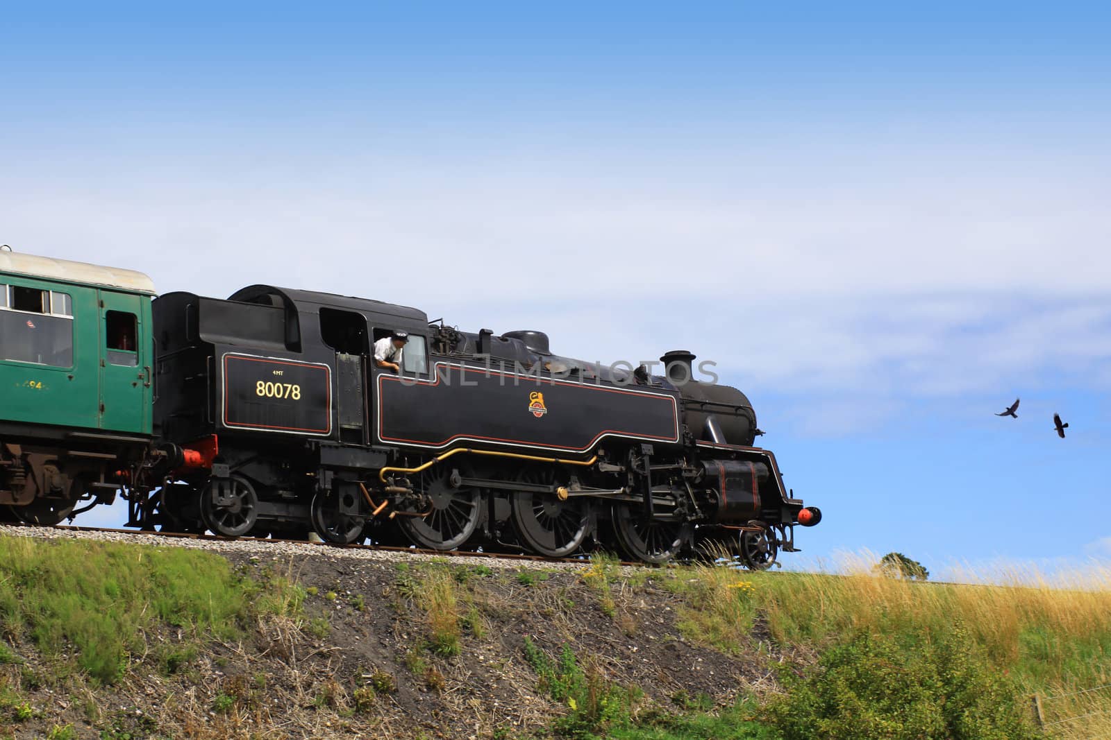 A steam engine pulling a passenger carriage on the track along the Swanage railway network. Location in Dorset UK.