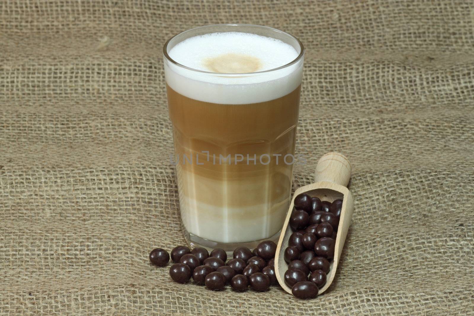 Latte Macchiato in glass with coffee grain on brown background