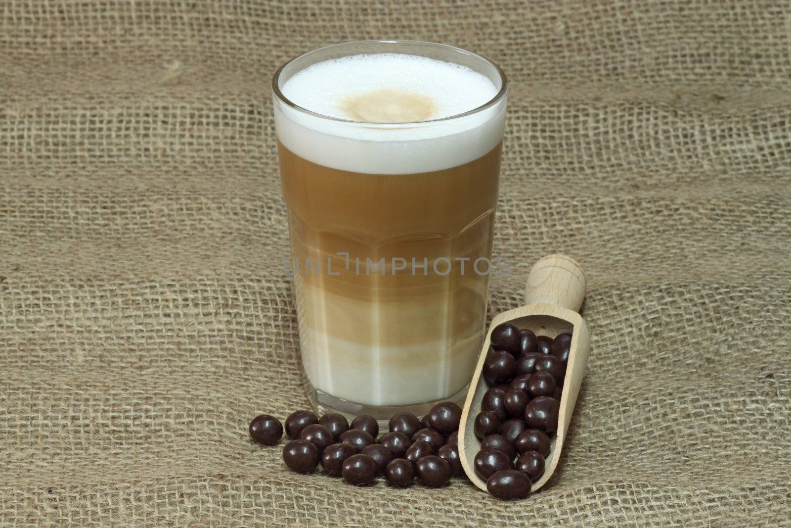 Latte Macchiato in glass with coffee grain on brown background
