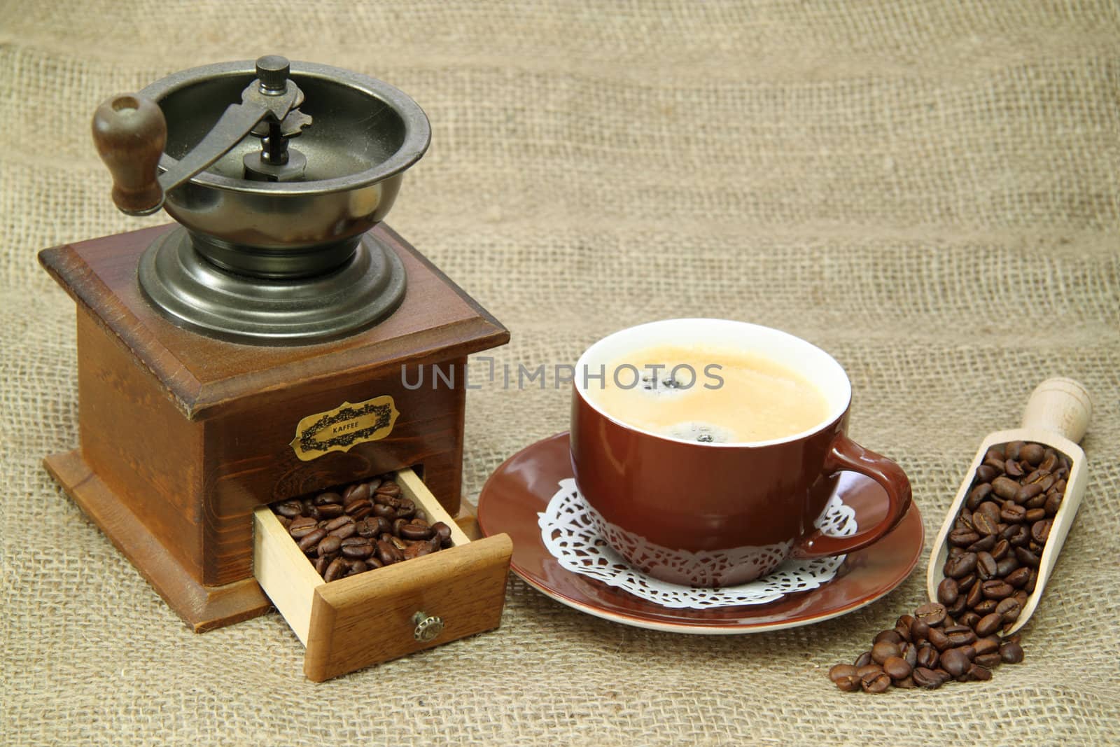 Delicious coffee with vintage coffee mill on brown background