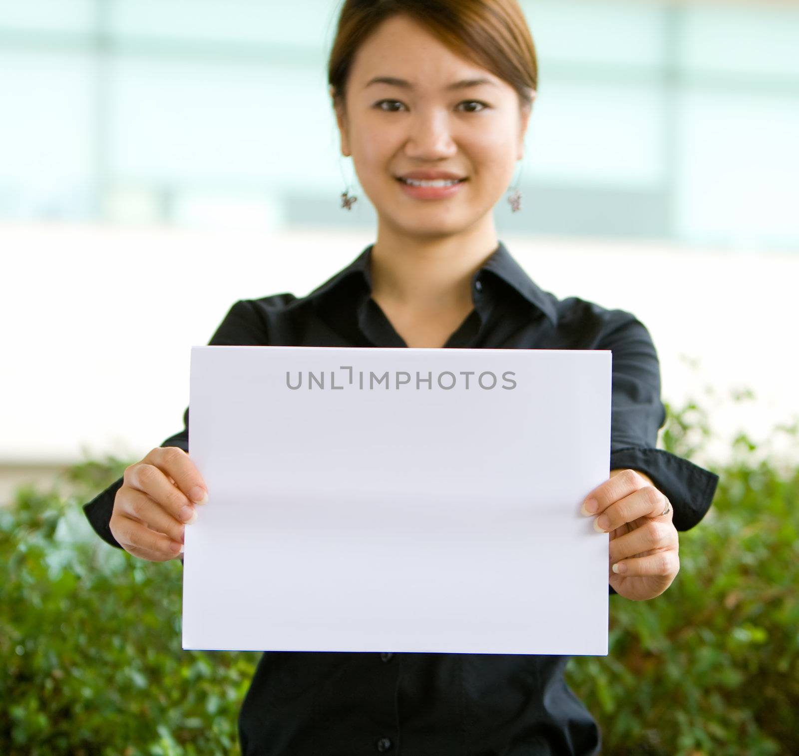 Young asian business woman holding a blank white paper for text