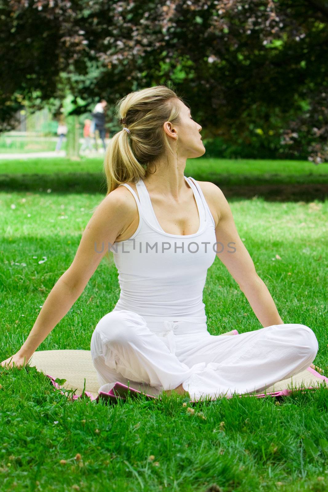 Blonde girl in nature green park exercising yoga, fitness program